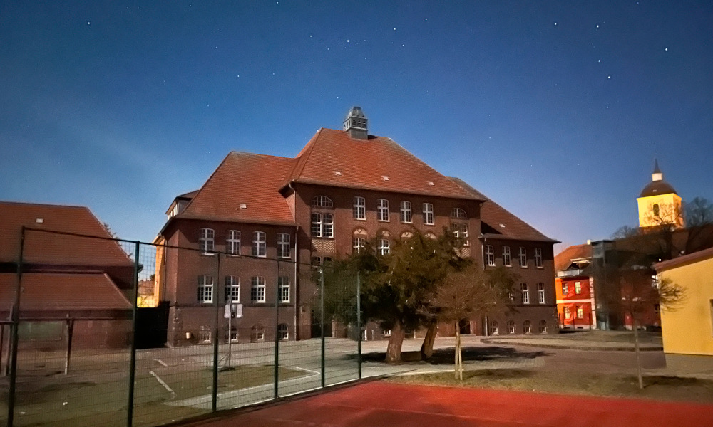 Foto des Schulgebäudes. Nachtaufnahme. Sternenhimmel.